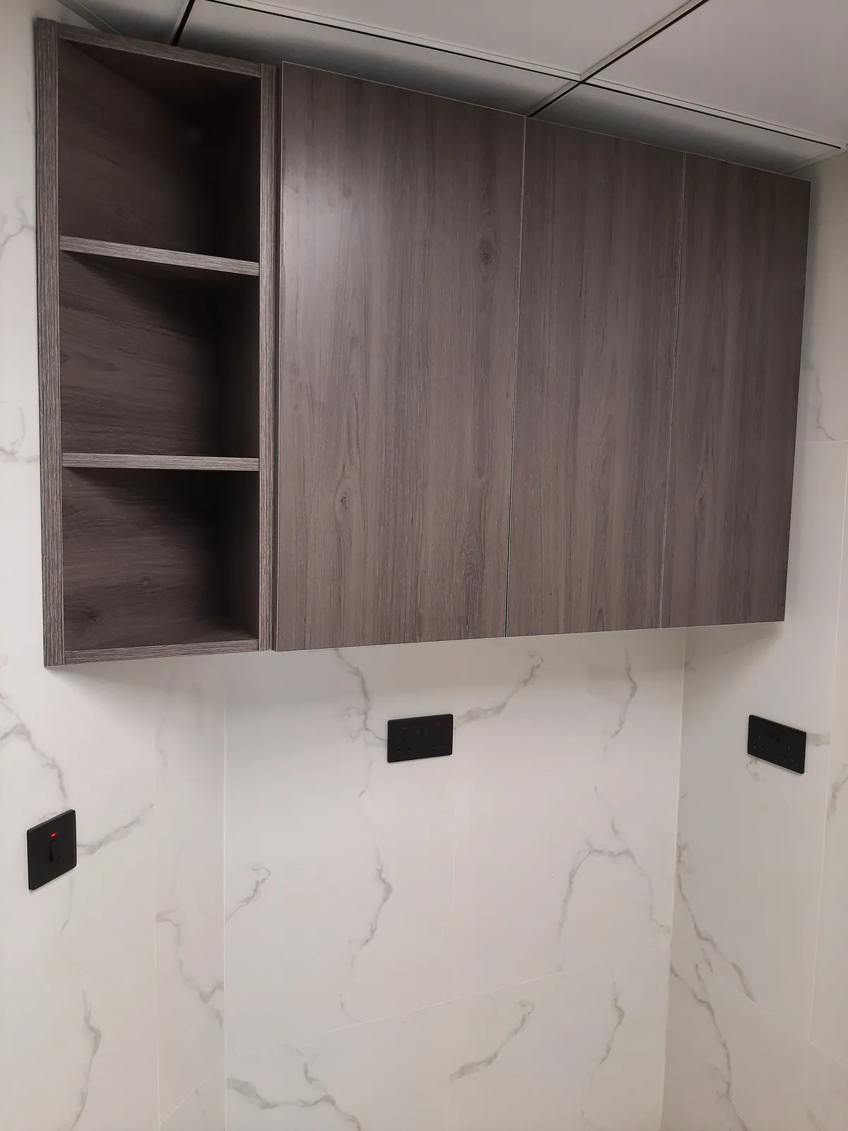 Upper gray wood cabinets installed against a marble-look backsplash