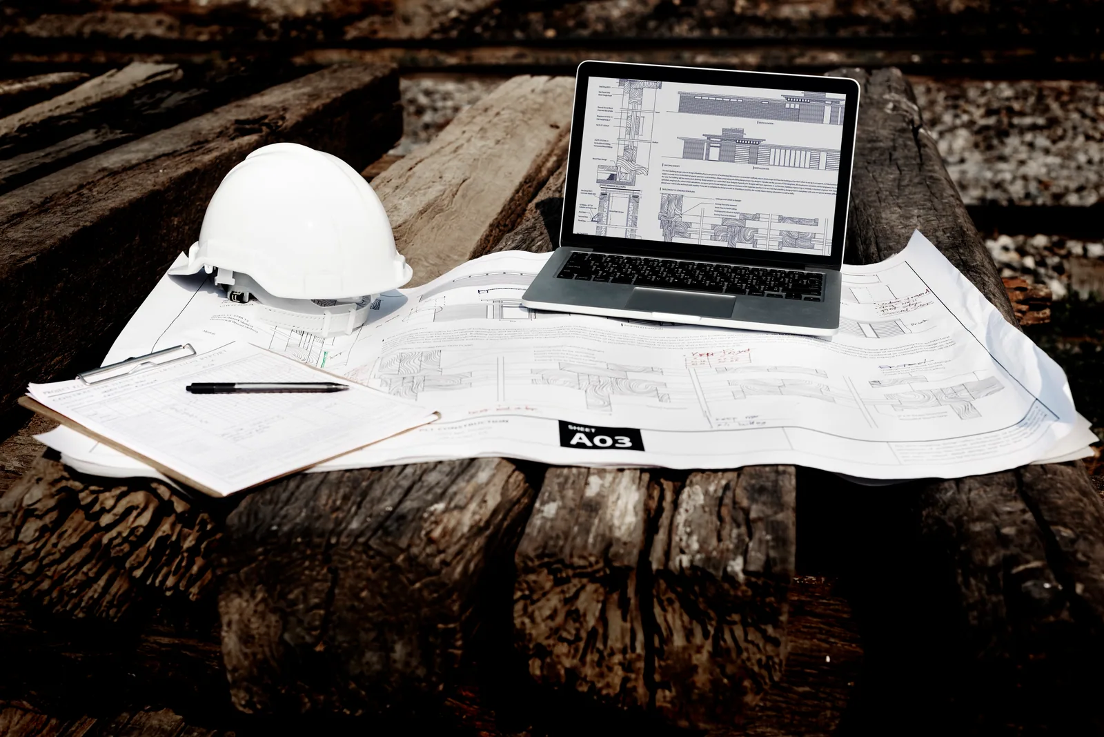 Construction plans, safety helmet and laptop prepared for technical project planning
